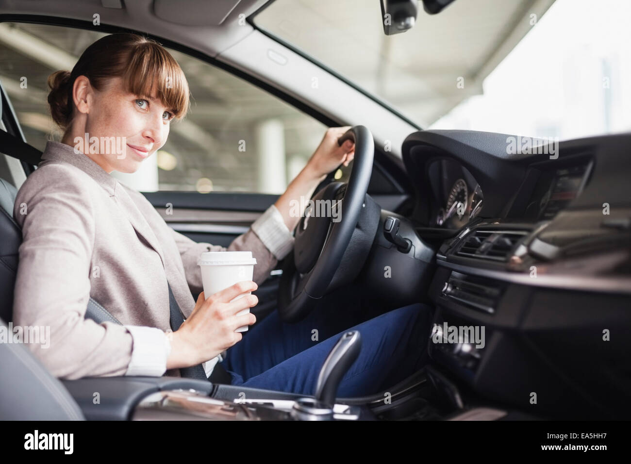 Deutschland, Hessen, Frankfurt, Porträt von lächelnden Geschäftsfrau fahren Autos mit Kaffee in der Hand gehen Stockfoto