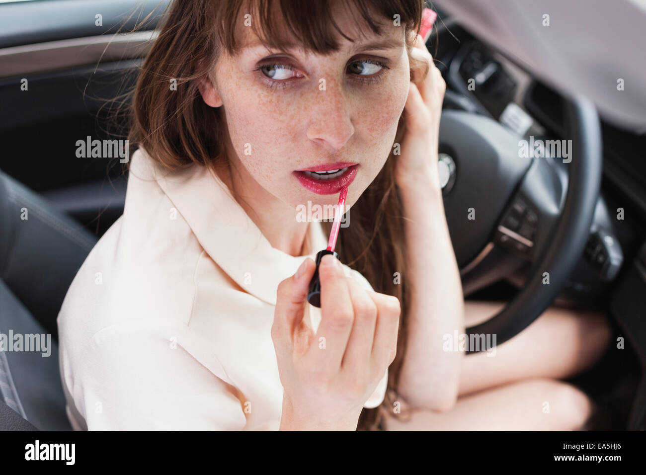 Porträt der Geschäftsfrau sitzen in ihrem Auto Auftragen von Lippenstift Stockfoto