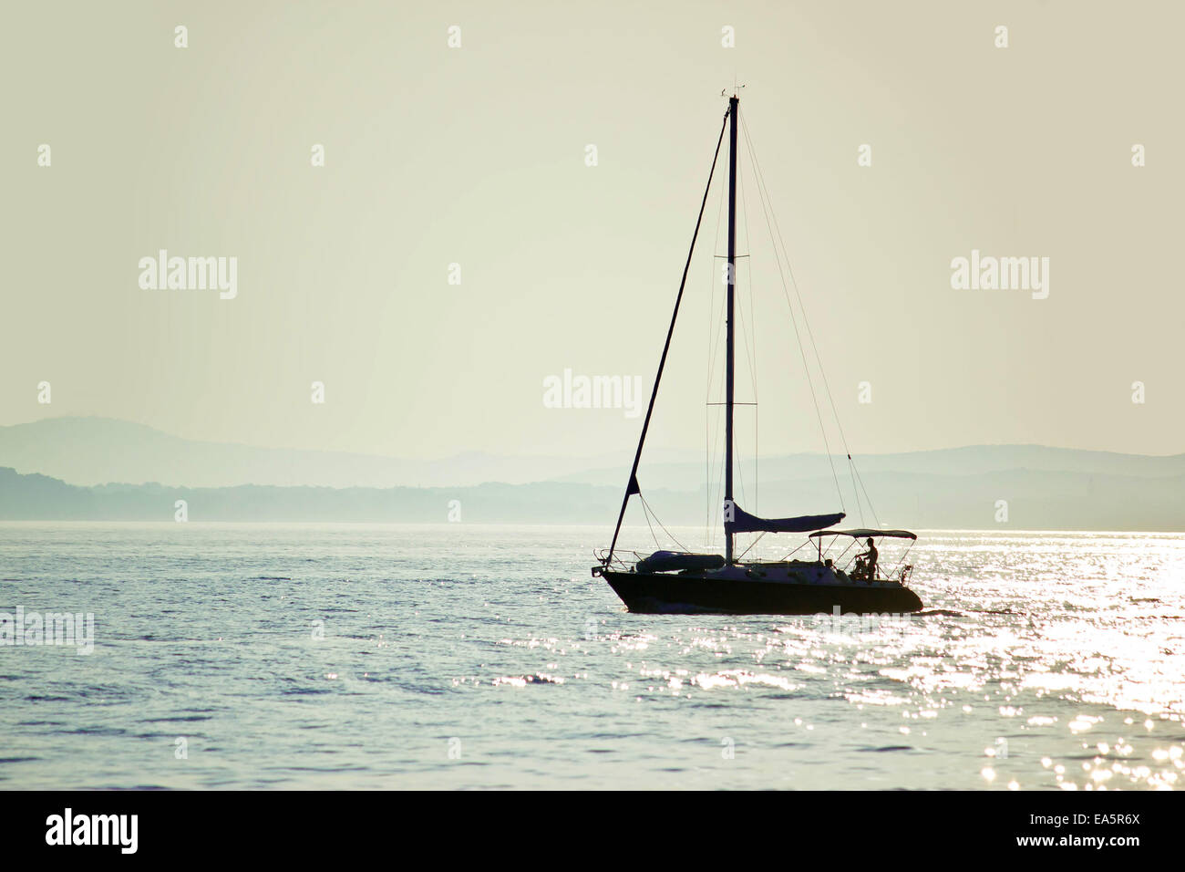 Segelboot-Silhouette auf dem offenen Wasser Stockfoto