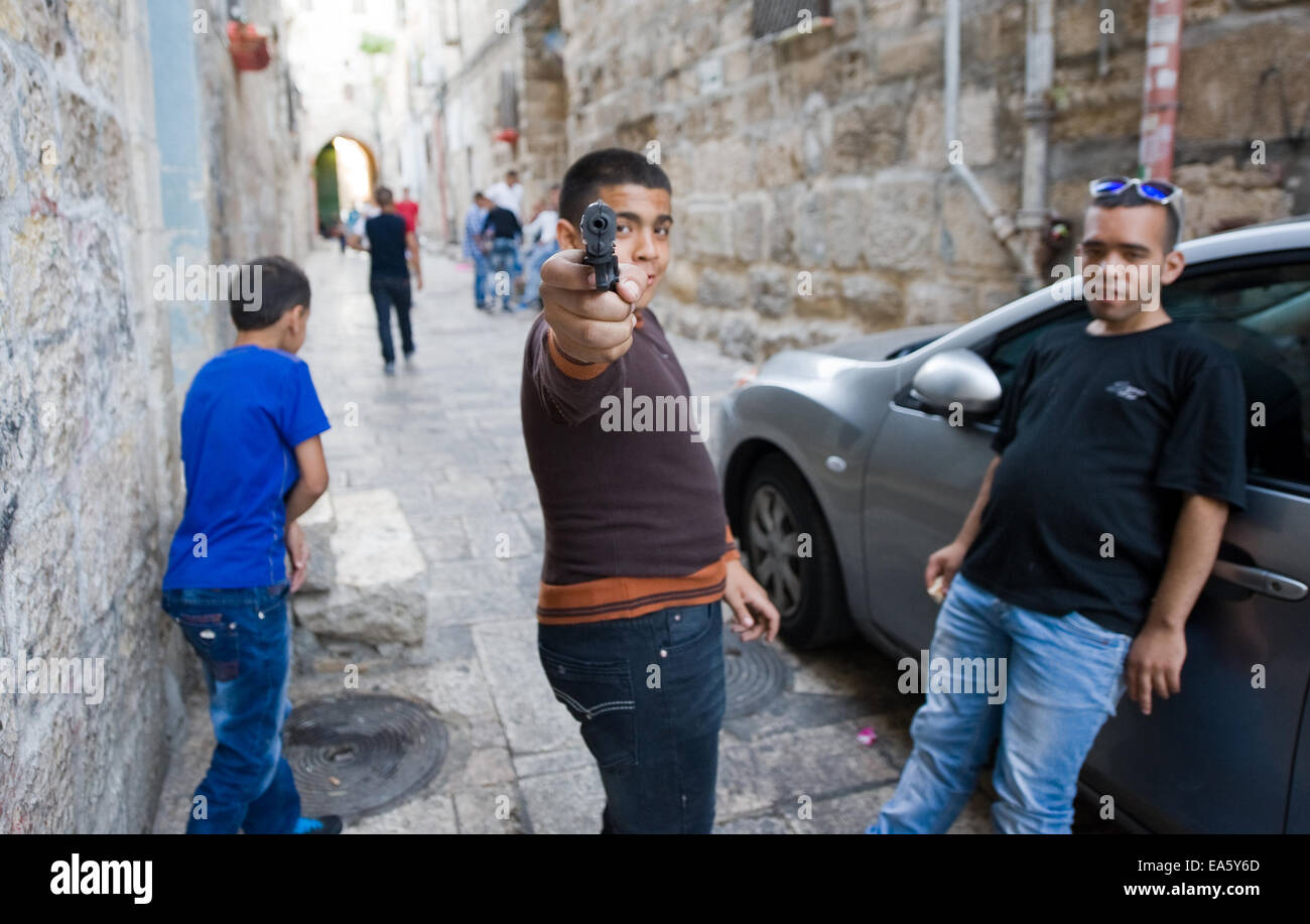 Drei junge muslimische Jugendliche spielen "Kriegsspiele" auf den Straßen im muslimischen Viertel in Jerusalem. Stockfoto