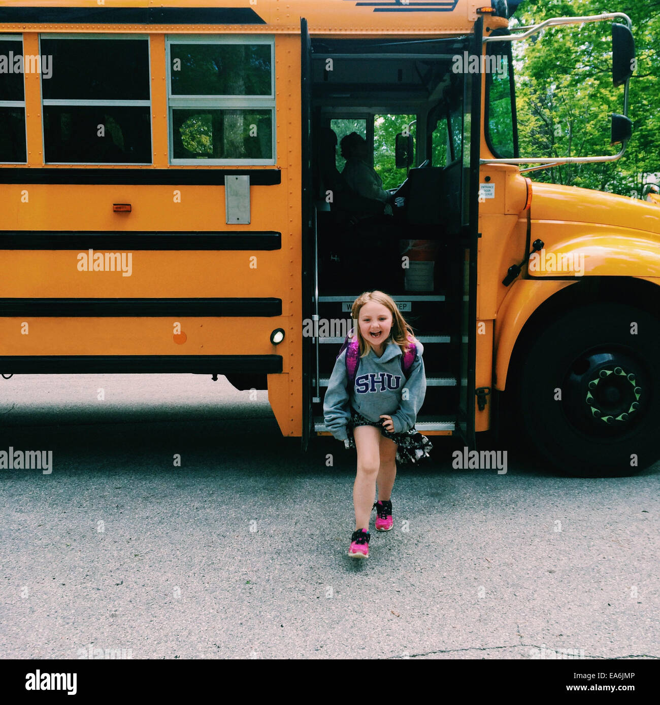 Lächelndes Mädchen, das aus dem Schulbus kommt, Wisconsin, USA Stockfoto