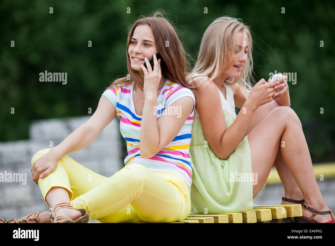 Mädchen auf einer Bank mit Handys Stockfoto