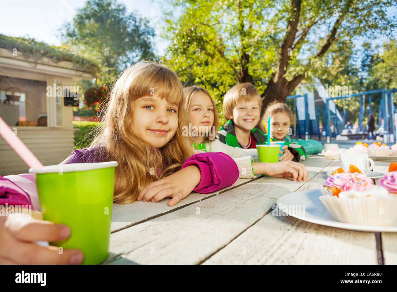 Glückliche Gruppe von Kindern mit Tassen und Kuchen sitzen Stockfoto