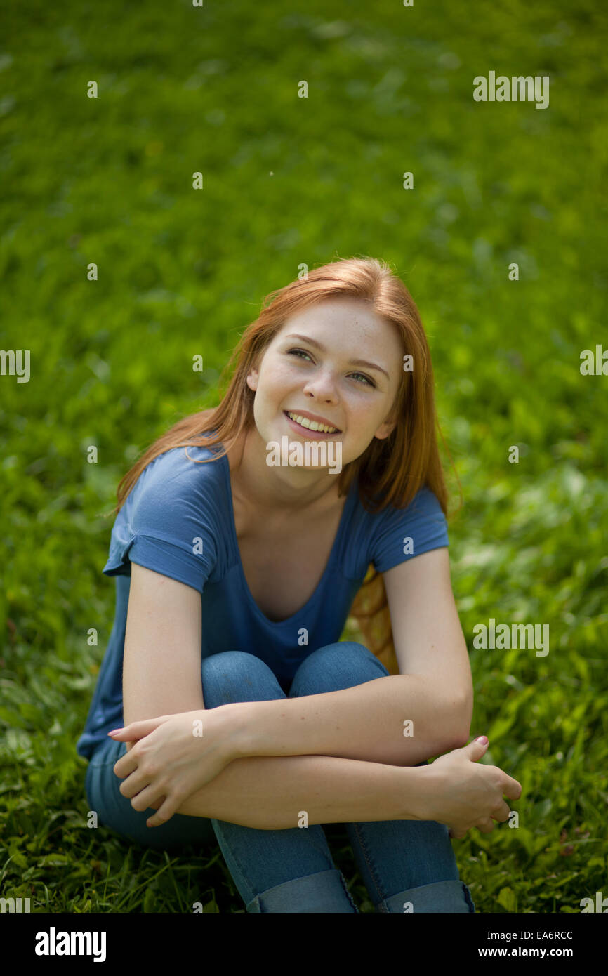 schöne rothaarige Mädchen sitzen auf dem Rasen Stockfoto