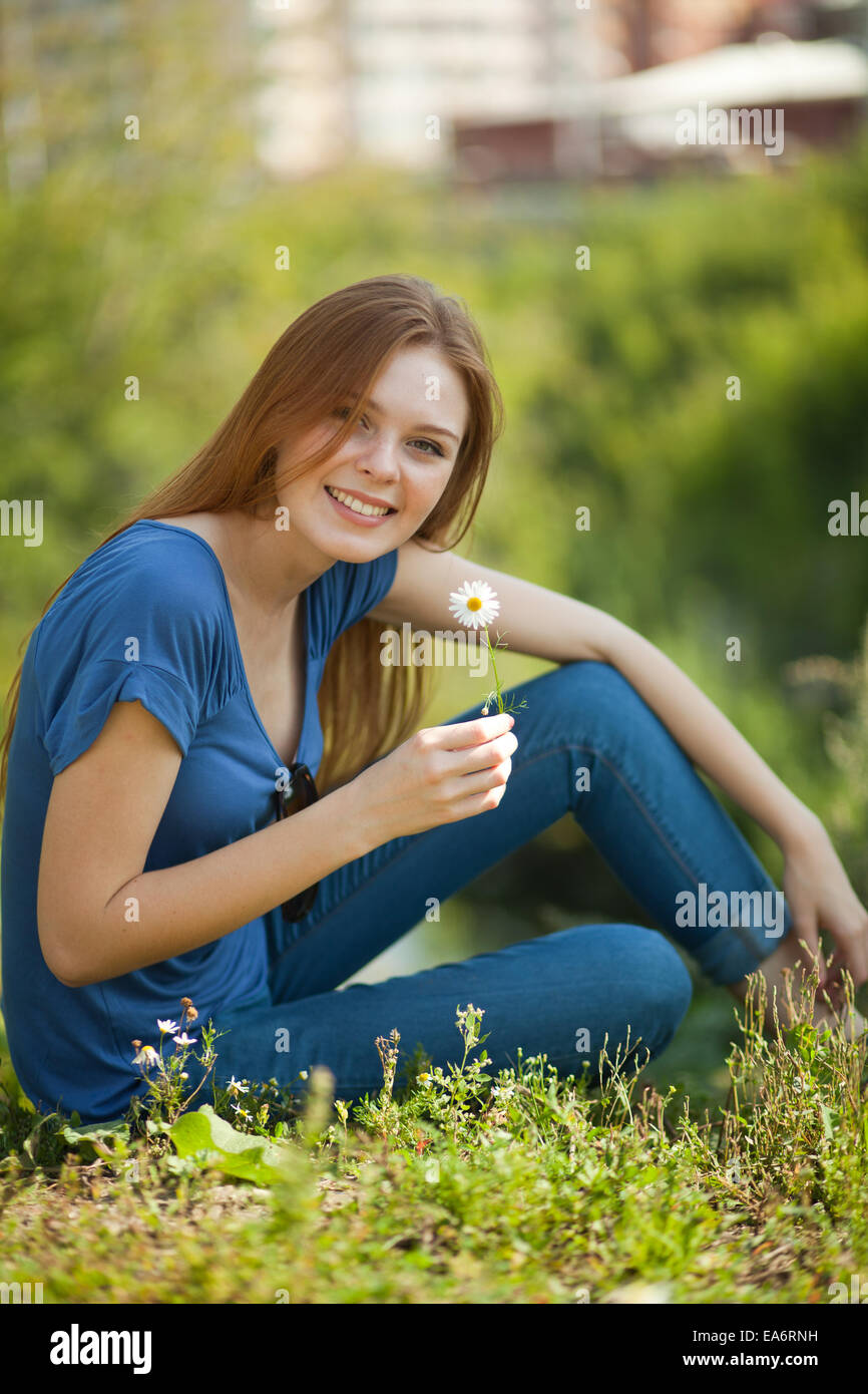 Mädchen mit Gänseblümchen im Gras sitzt und schnüffeln Stockfoto