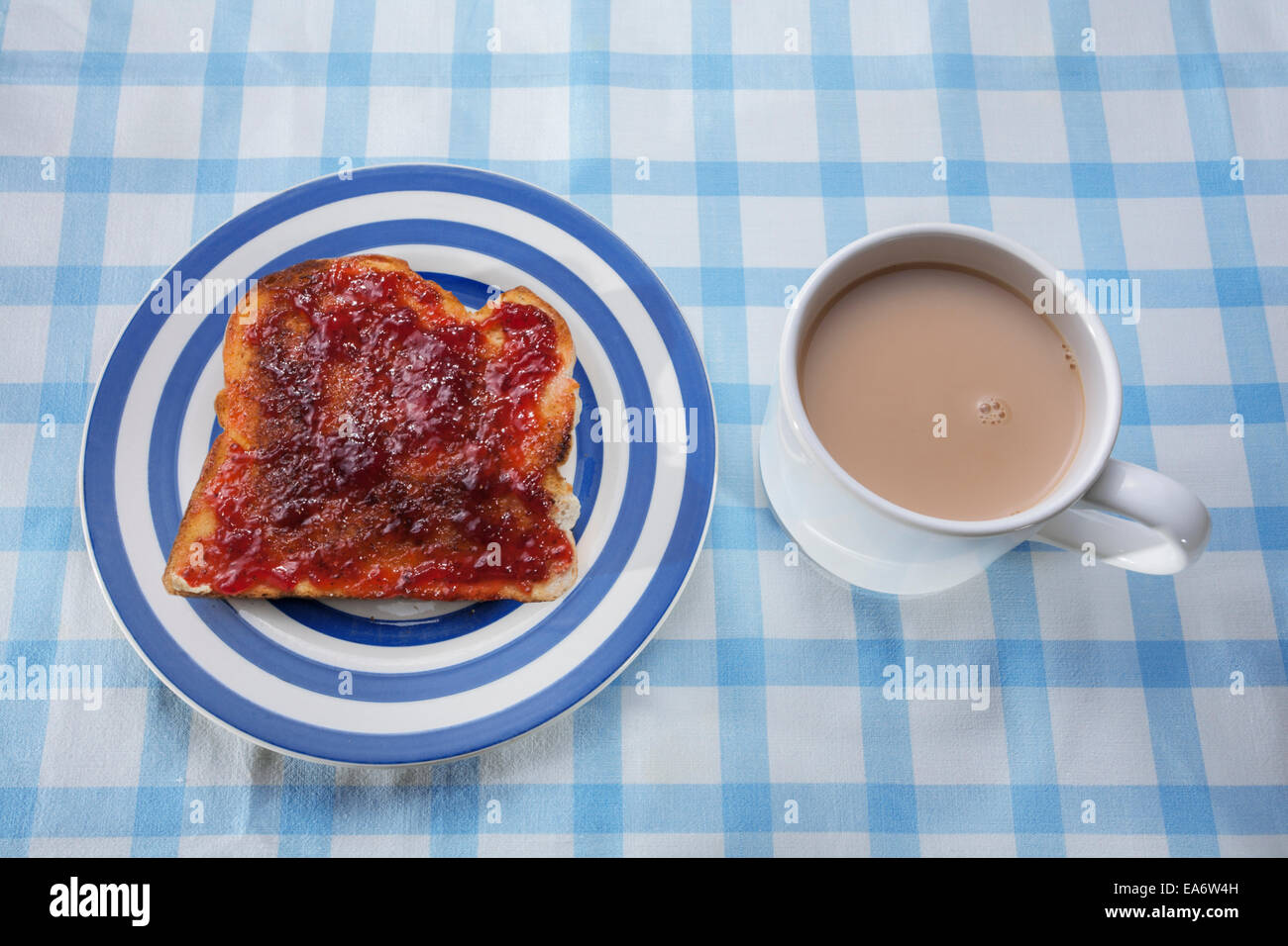 Marmelade auf Toast und eine Tasse Tee auf einer Tischdecke überprüfen. Stockfoto