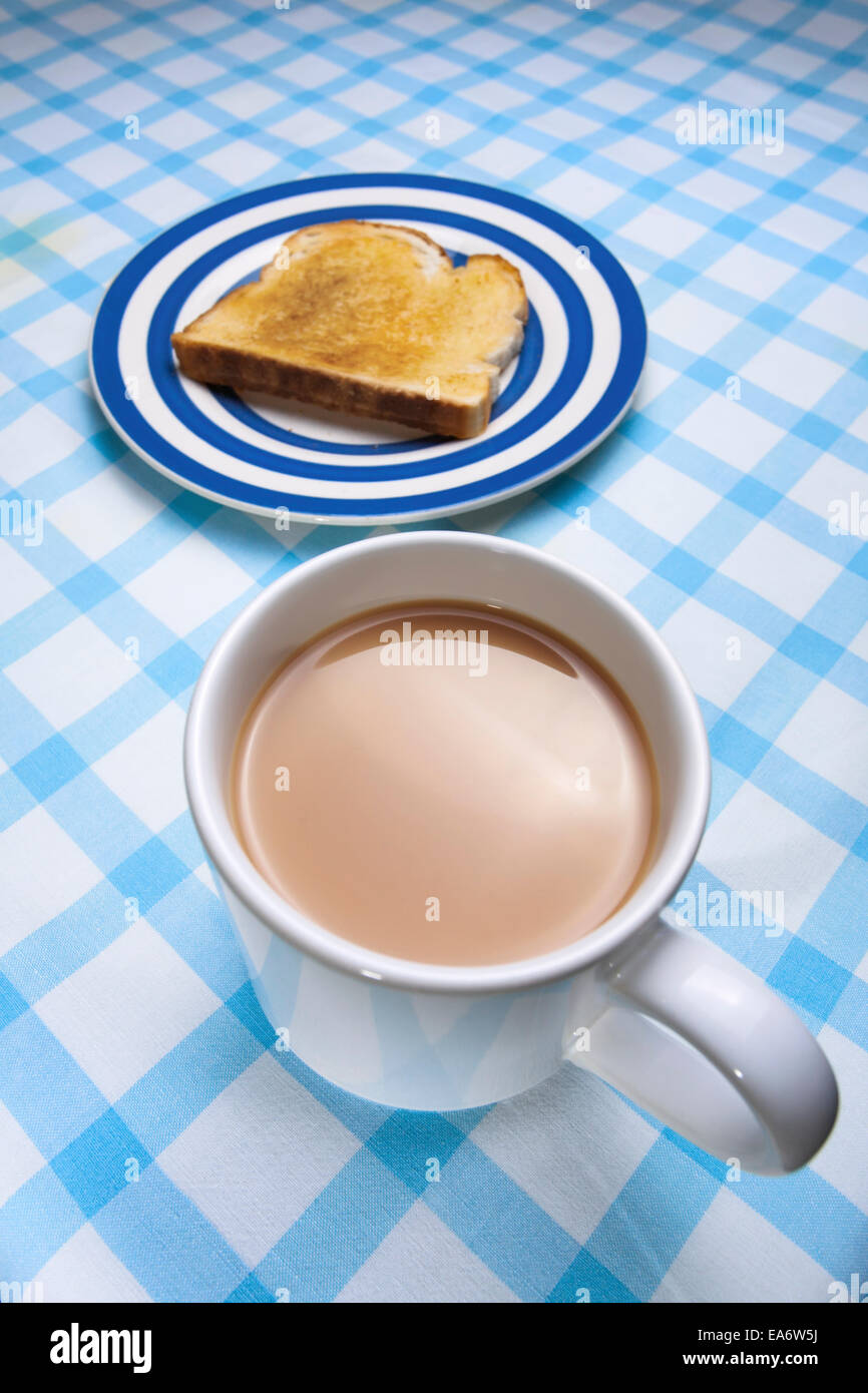 Mit Butter, Toast und eine Tasse Tee auf einer Tischdecke überprüfen. Stockfoto