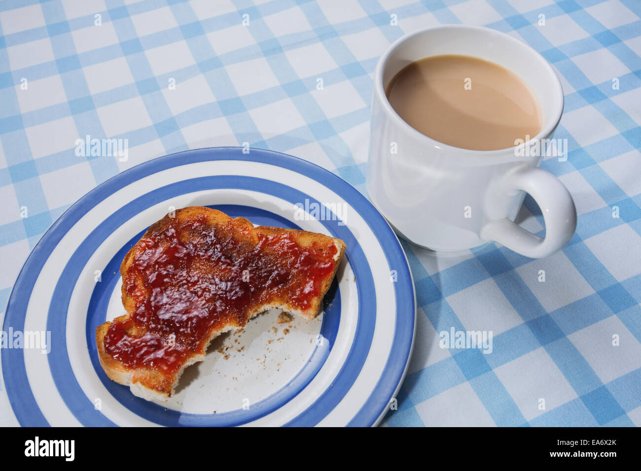 Marmelade auf Toast und eine Tasse Tee auf einer Tischdecke überprüfen. Stockfoto
