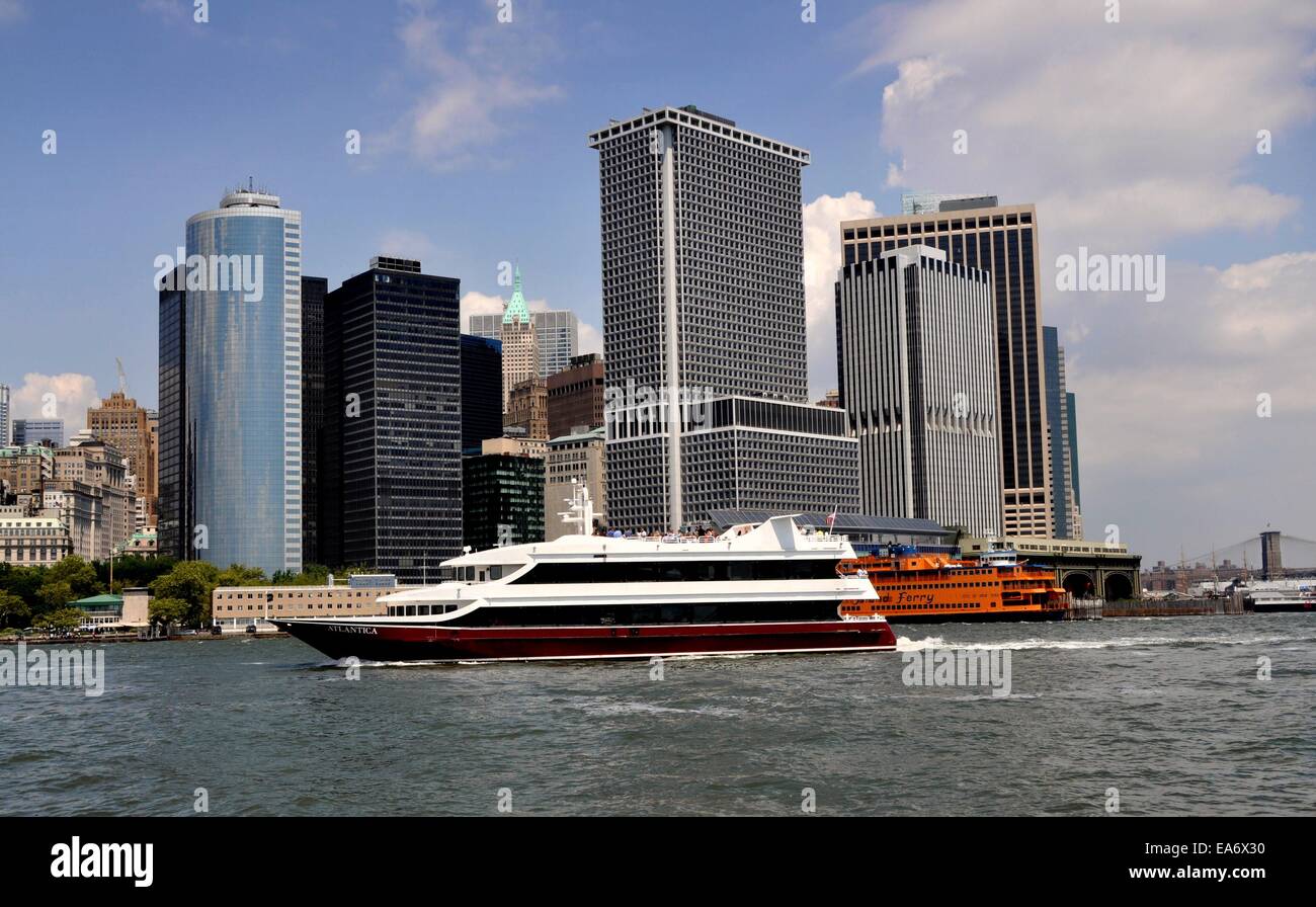 NYC: Die Luxus-Kreuzfahrt-Yacht, die Atlantica der Südspitze der Insel Manhattan, NYC mit seiner hohen Glastürmen übergibt Stockfoto