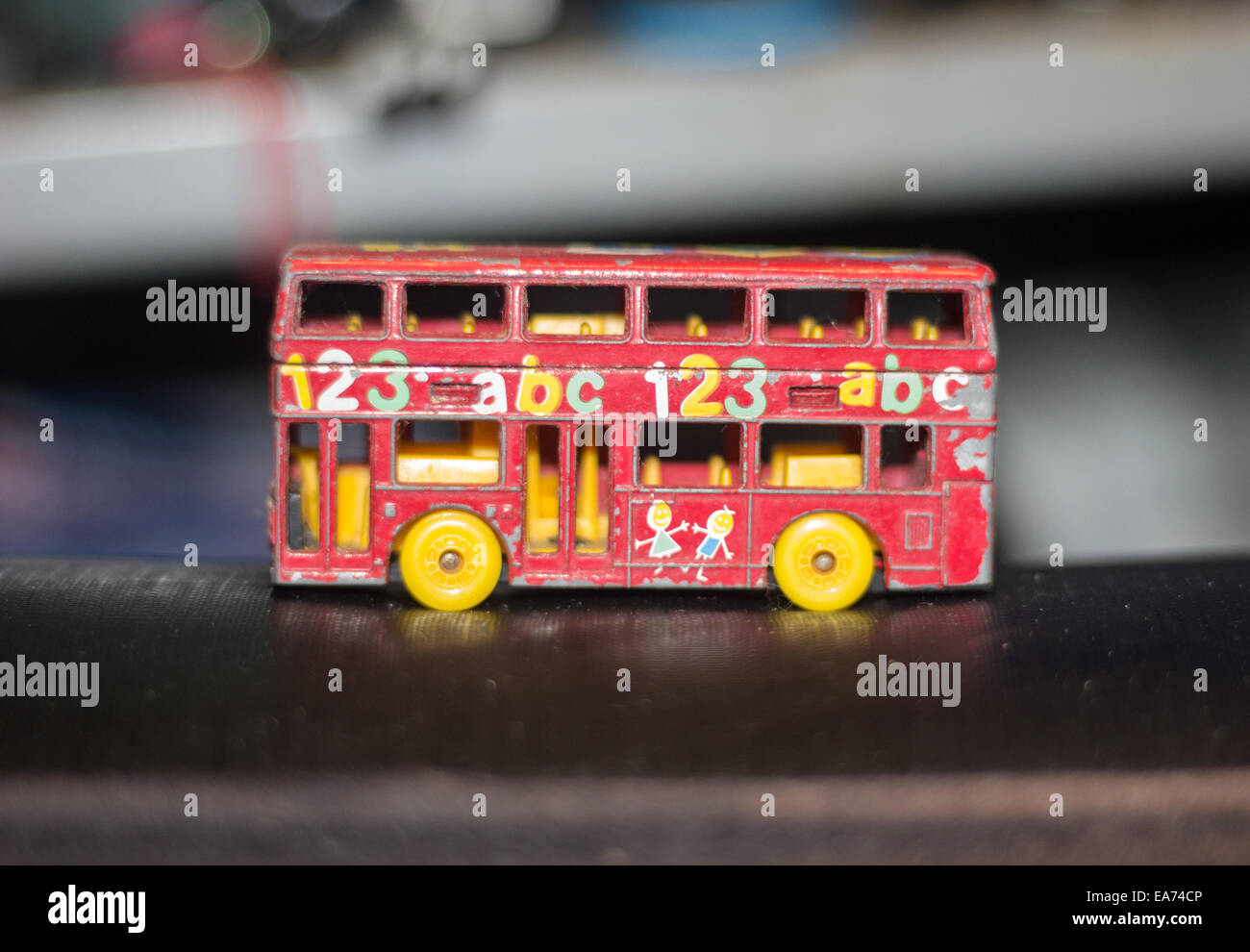 Ein roter Spielzeug-Modell-Bus mit 123 Abc auf der Seite mit gelben Rädern und keine Fenster in einer Garage gedruckt. Stockfoto