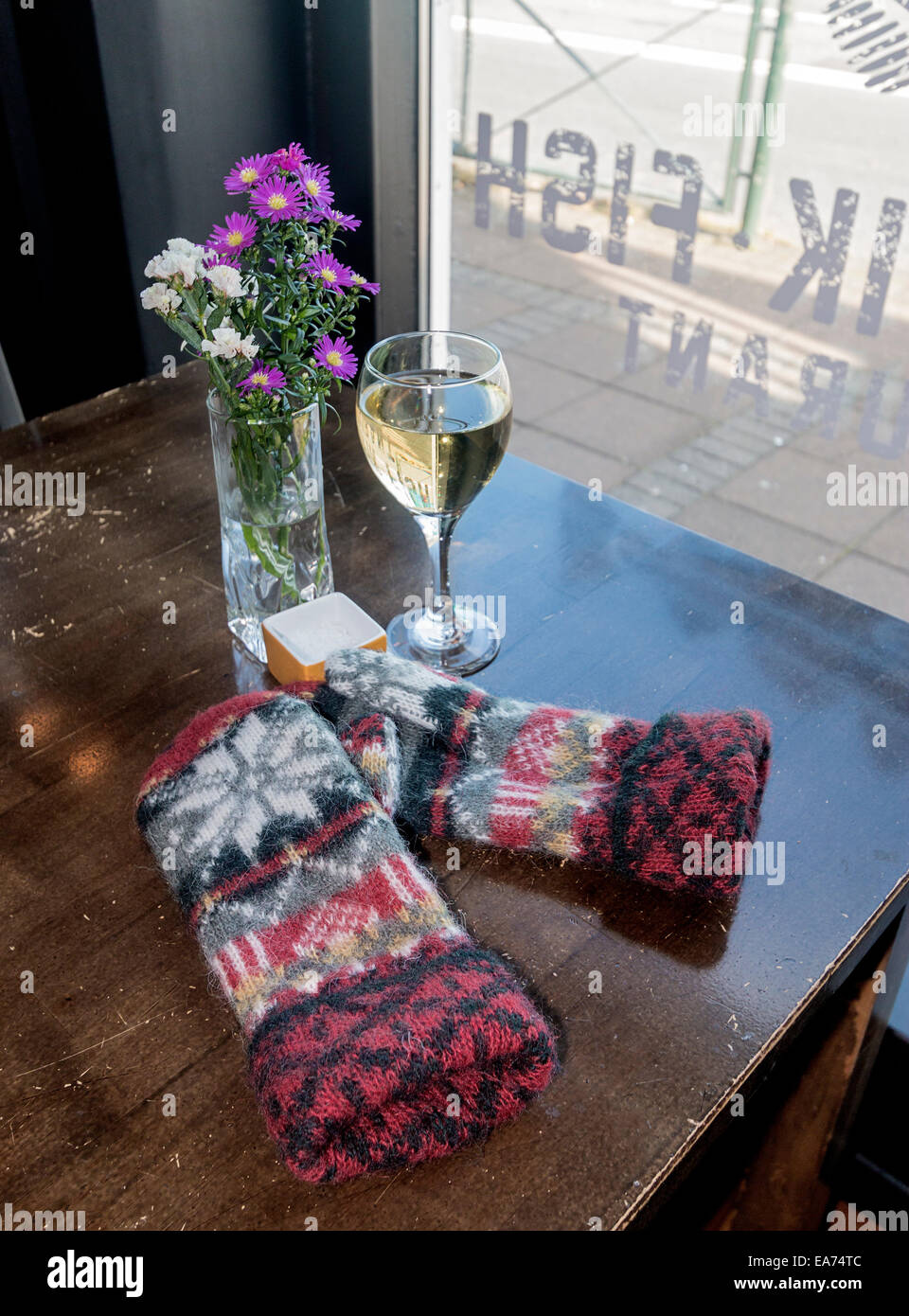 Wolle isländischer Fäustlinge, ein Glas Wein und Blumen in einem lokalen Restaurant in Reykjavik, Island. Stockfoto