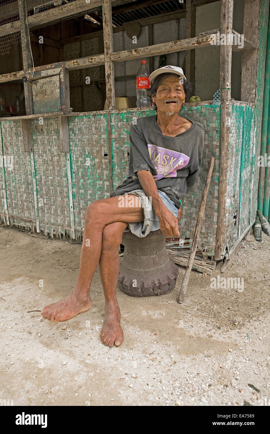 Ein Filipino Greis mit Arthritis sitzt eine Bambus-Hütte auf einem Hocker aus einem Autoreifen hergestellt. Stockfoto