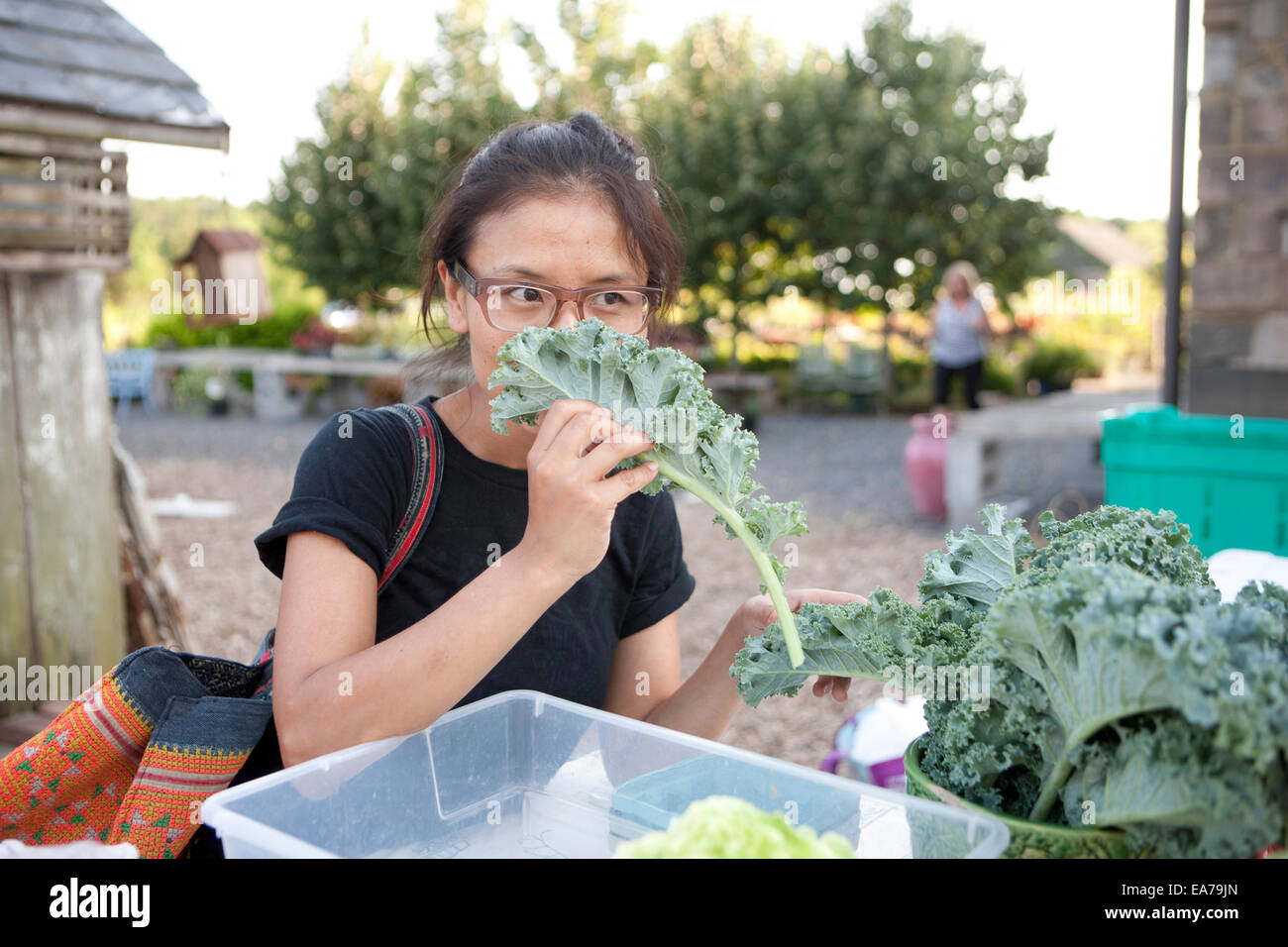 Junge Frau riechen Salat auf Open-Air-Markt Stockfoto