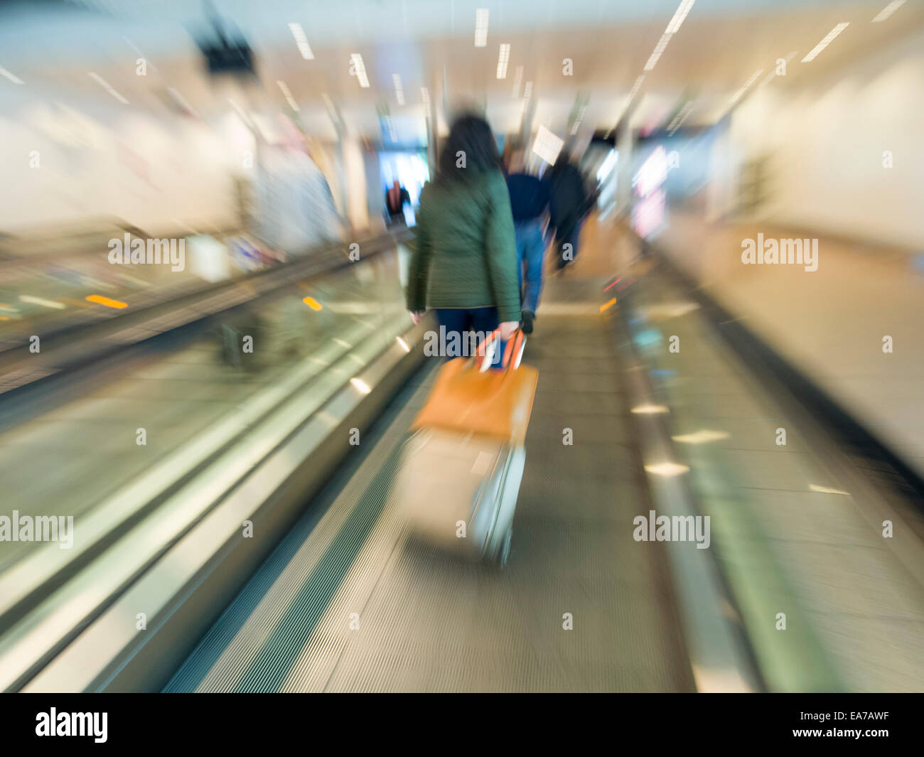Rückansicht des Menschen mit rollenden Koffern auf ein Laufband am Flughafen Stockfoto