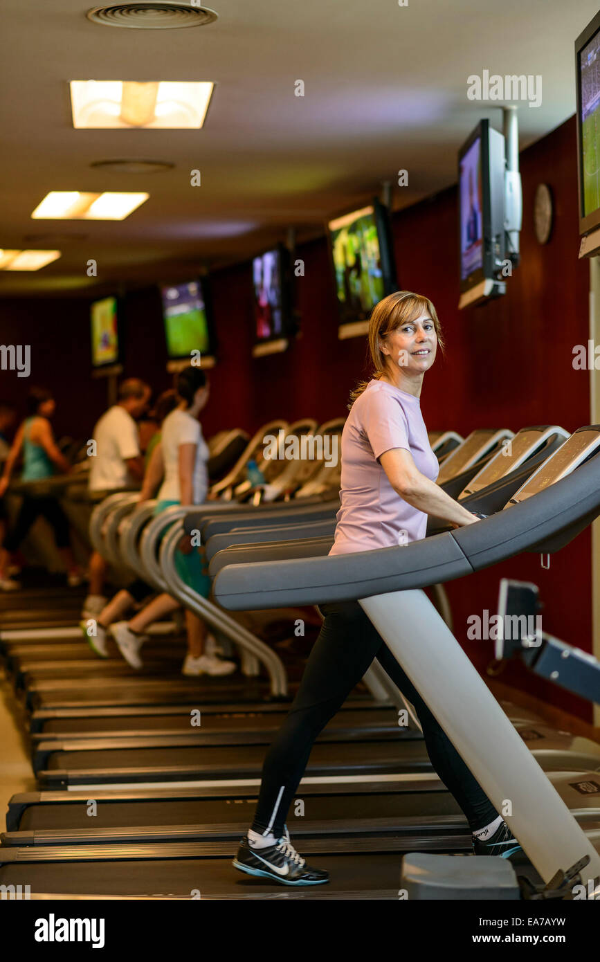 Reife Frau gehen auf Laufband im Fitnessstudio Stockfoto