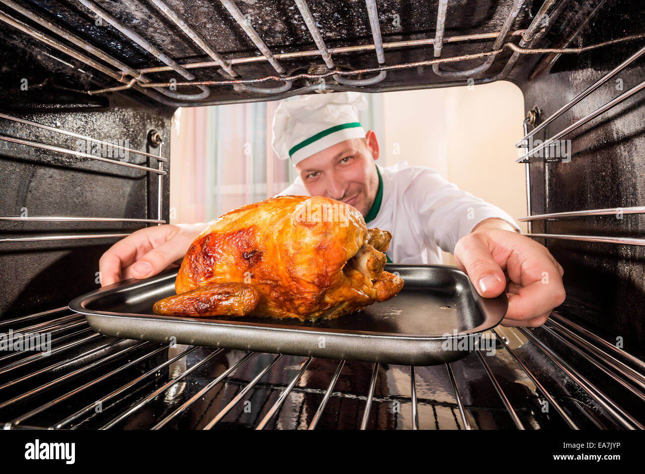 Chefkoch Brathähnchen (Schwerpunkt Huhn) in den Ofen, Blick aus dem Inneren des Ofens. Kochen in den Ofen. Stockfoto