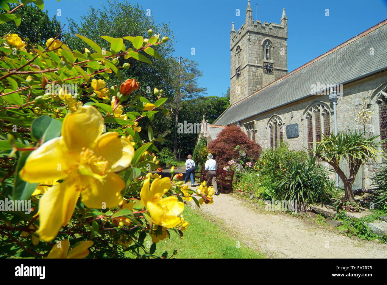 Außenansicht des Zennor Kirche aus dem Garten mit gelb blühender Strauch in den Vordergrund & zwei Menschen zu Fuß Weg, chu Stockfoto