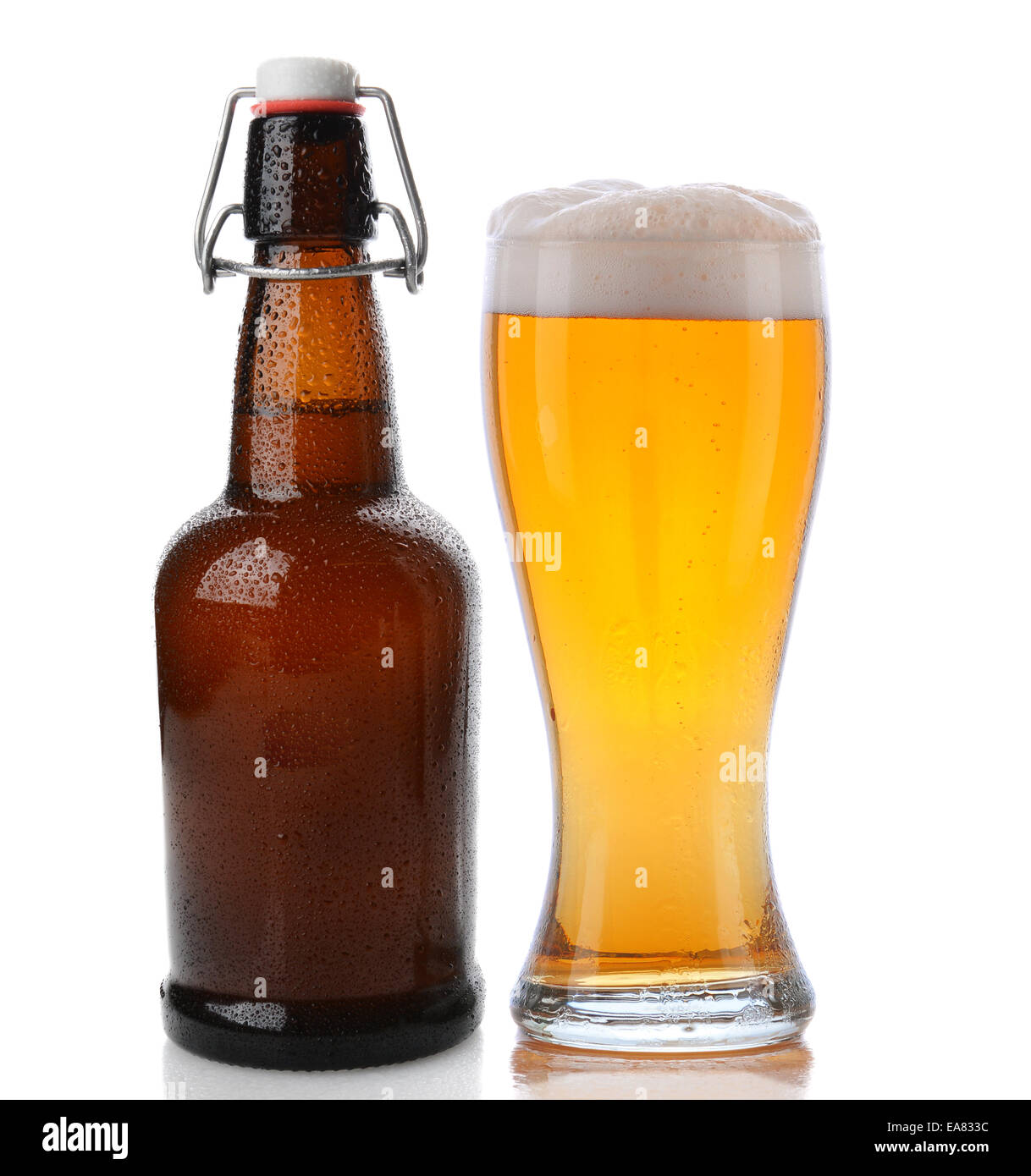 Nahaufnahme von einem Glas Bier mit einem schaumigen Kopf neben einer Schaukel Top braune Bierflasche. Geradeaus weiter Schuss auf einen weißen Hintergrund mit Stockfoto