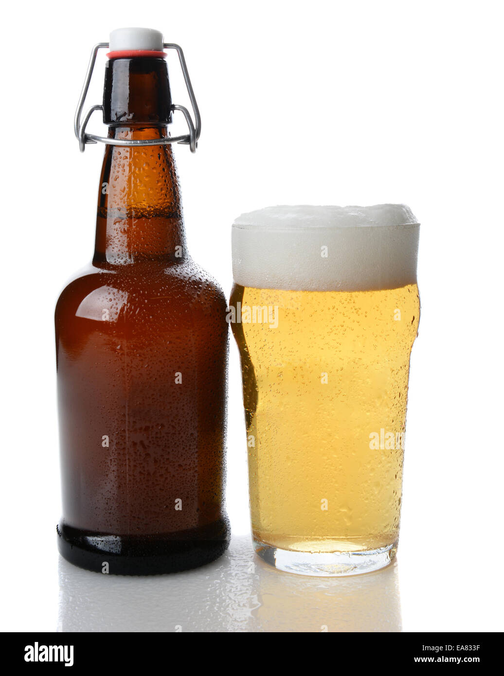 Nahaufnahme einer Schaukel Top braune Bierflasche neben einem vollen Glas Bier mit einem schaumigen Kopf. Geradeaus weiter Schuss auf einem weißen Hintergrund w Stockfoto