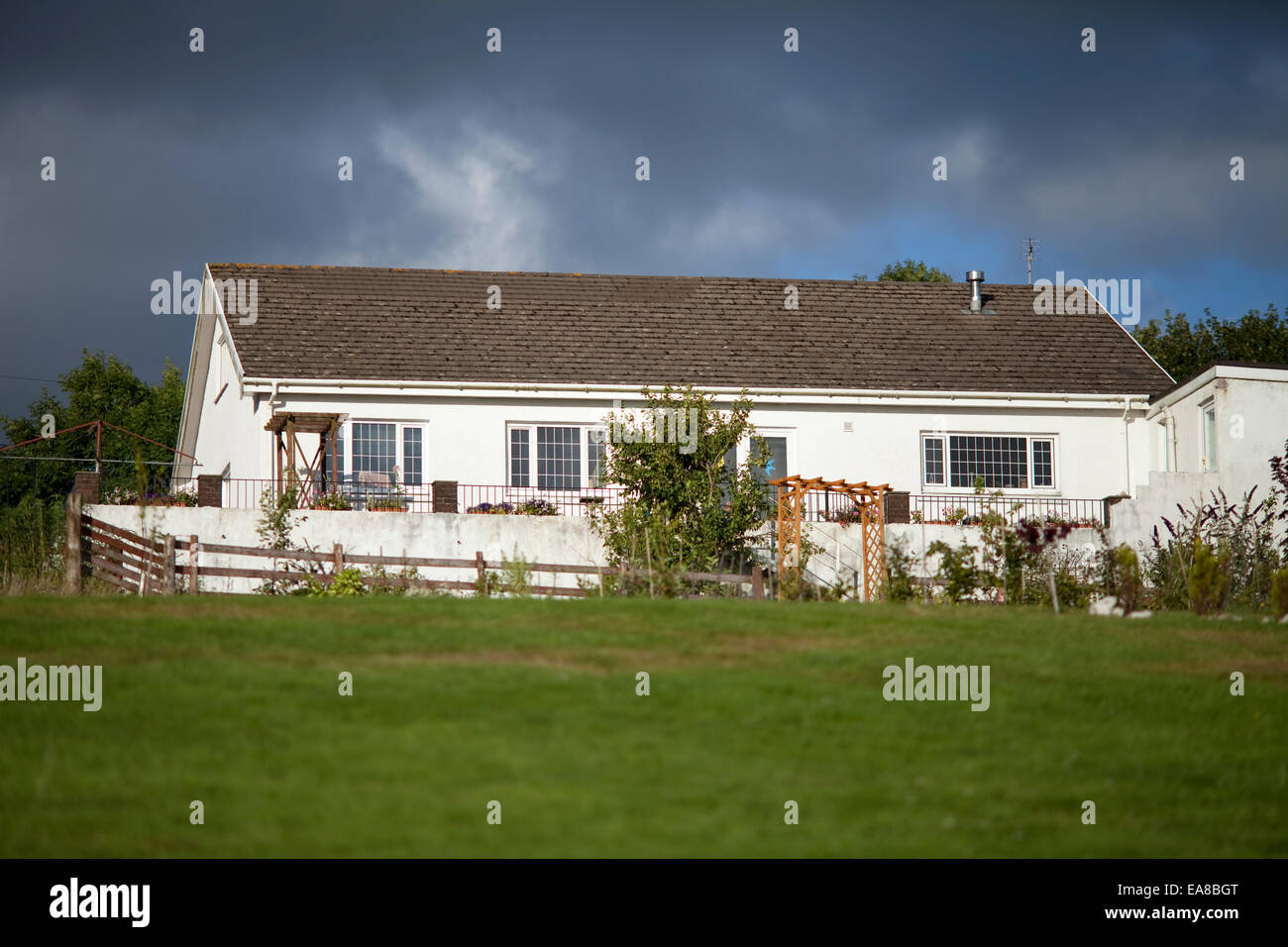 Rückansicht eines typisch englischen britische Bungalows, in Carmarthenshire Wales genommen.  Aus dem Garten gegen einen stürmischen Himmel genommen. Stockfoto