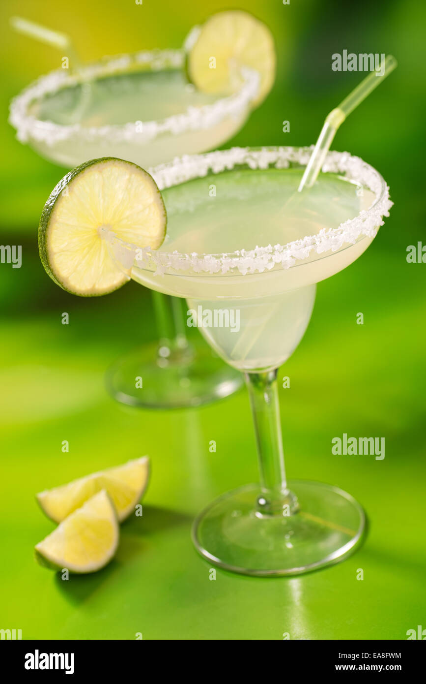 Zwei Tequila Margaritas mit Tequila, Kalk und Salz gegen einen pulsierenden abstrakten grünen Hintergrund. Stockfoto