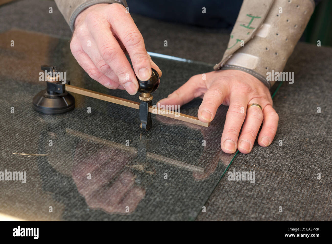 Nahaufnahme eines Arbeiters Händen messen und schneiden eine Glasscheibe mit einem Glasschneider Stockfoto