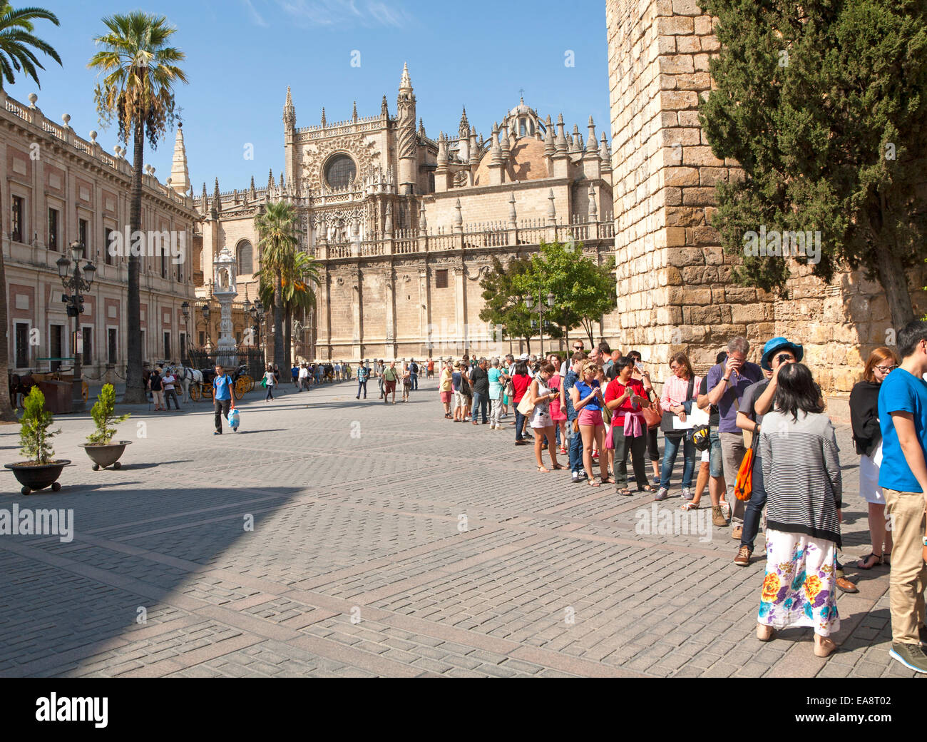 Linie von Touristen, die Schlange, um das Alcazar in Sevilla, Spanien mit dem Dom im Hintergrund eingeben Stockfoto