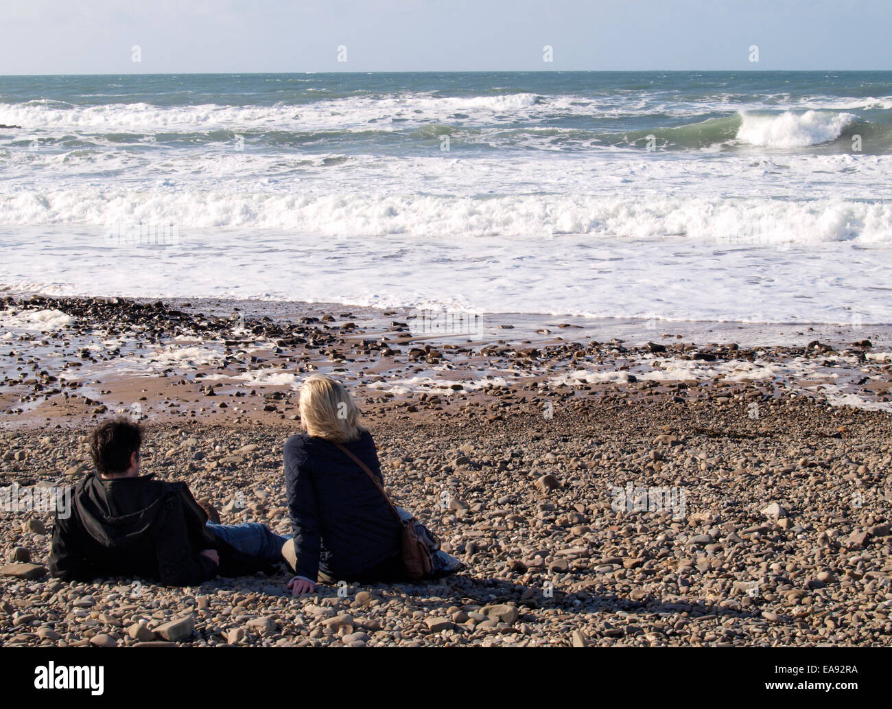 Paar am Strand an einem sonnigen Herbsttag saß Crooklets Strand, Bude, Cornwall, UK Stockfoto
