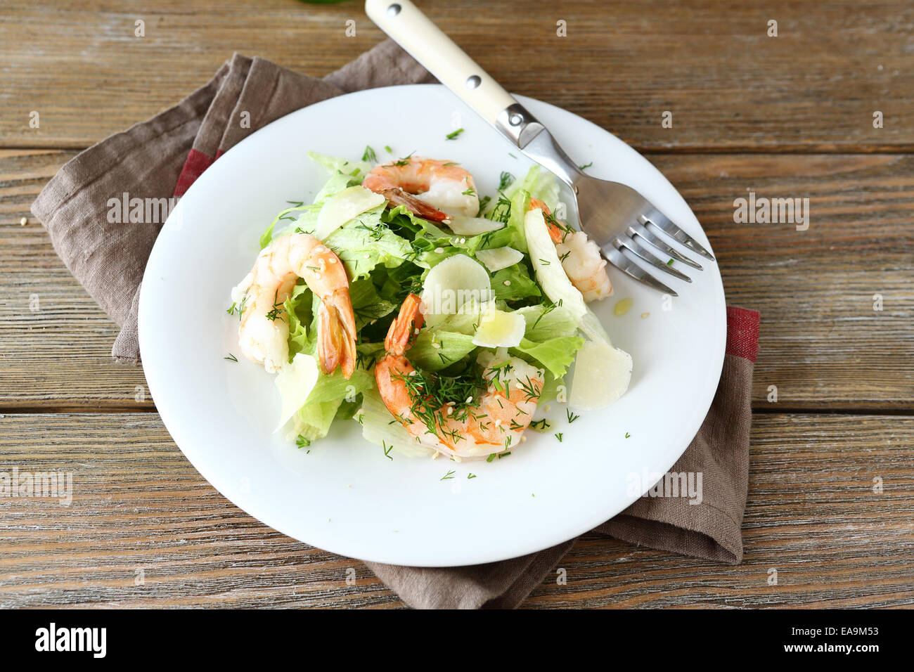 Salat mit Garnelen, Salat und Parmesan auf einem Teller, hölzernen Hintergrund Stockfoto