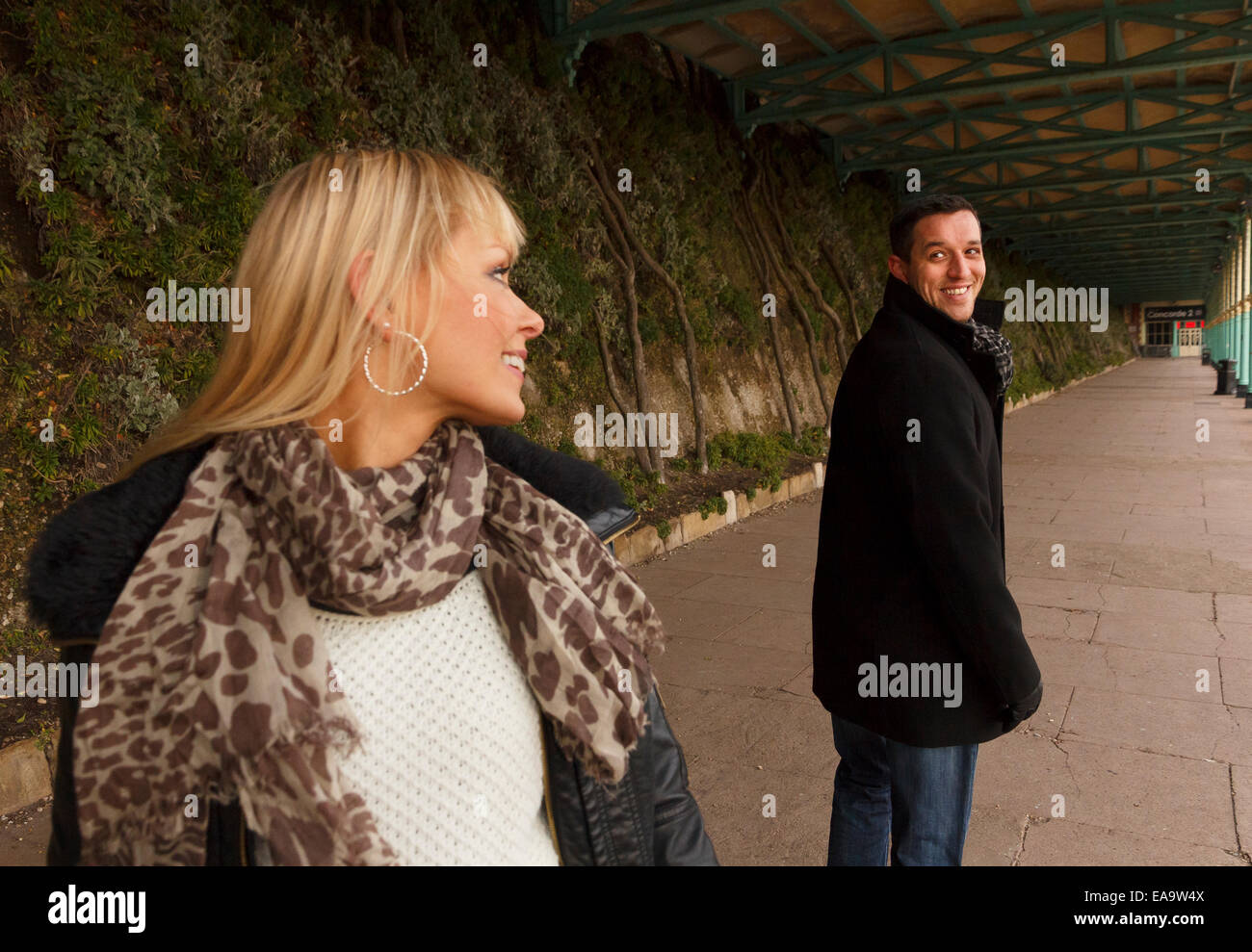 Ein Mann und Frau zu Fuß zurückblicken auf ihre Schultern und Lächeln Stockfoto