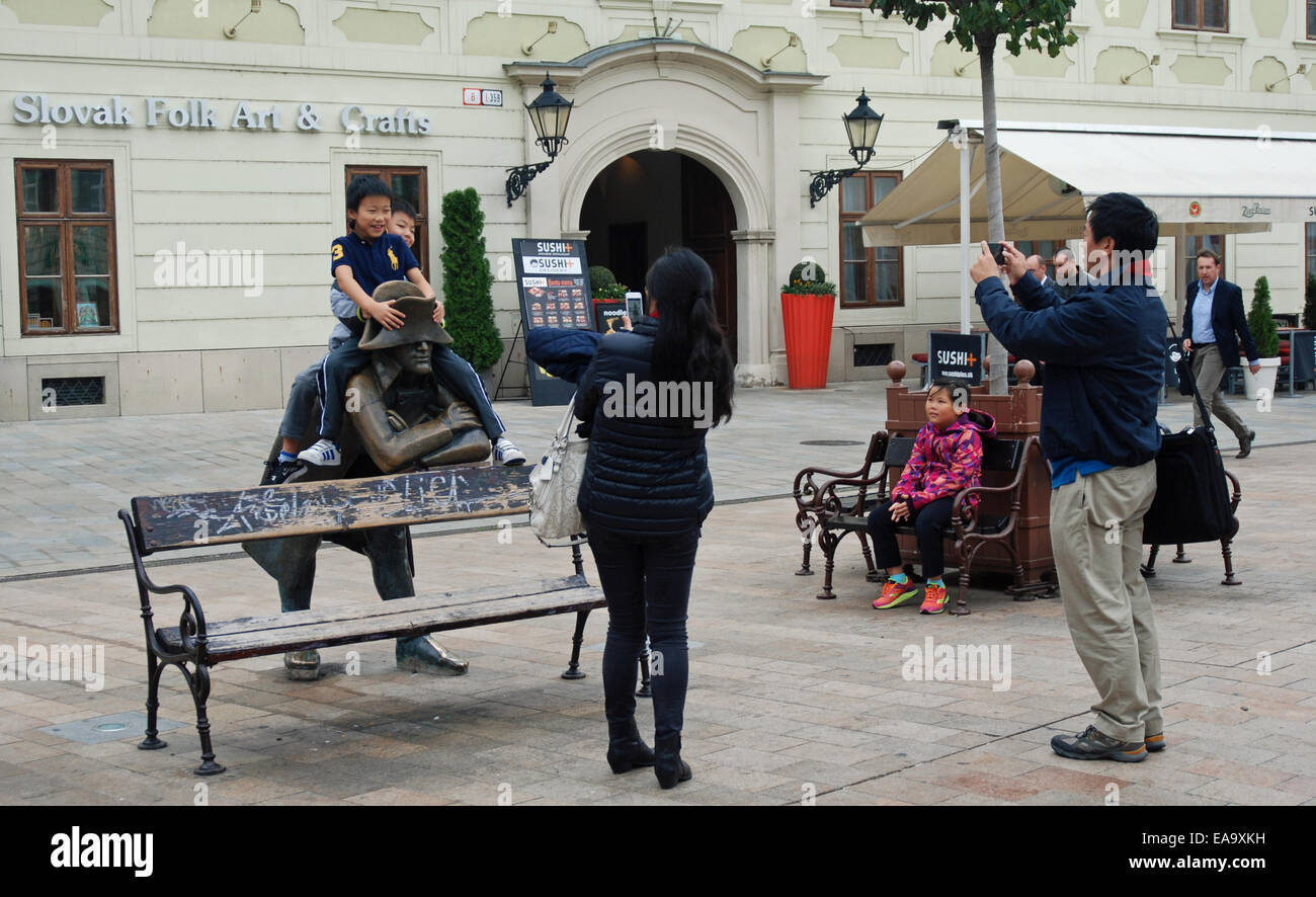 Chinesische Touristen fotografieren ein Kind sitzt auf Statue in den wichtigsten Platz von Bratislava Altstadt. Stockfoto