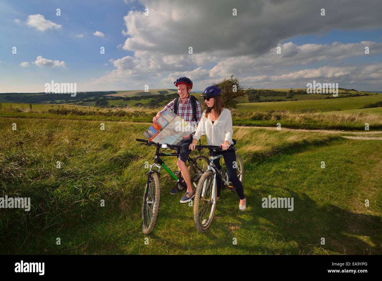 Ein junger Erwachsener paar Radfahrer Kartenlesen entlang der South Downs Way am Hintern Braue, Willingdon, Eastbourne, East Sussex. UK Stockfoto