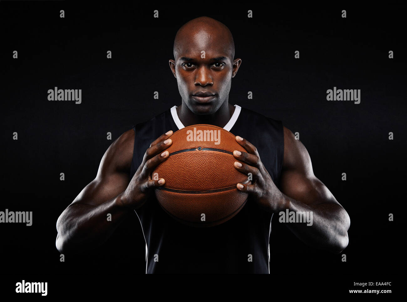 Porträt von Afro amerikanische männliche Basketball-Spieler mit einem Ball auf schwarzem Hintergrund. Passen Sie jungen Mann in Sportbekleidung mit Ball. Stockfoto