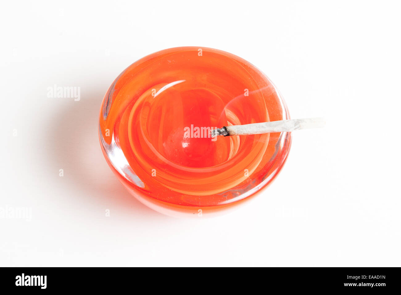 Ein rotes Glas Aschenbecher mit handgefertigten Zigarette rauchen isoliert auf weißem Hintergrund Stockfoto