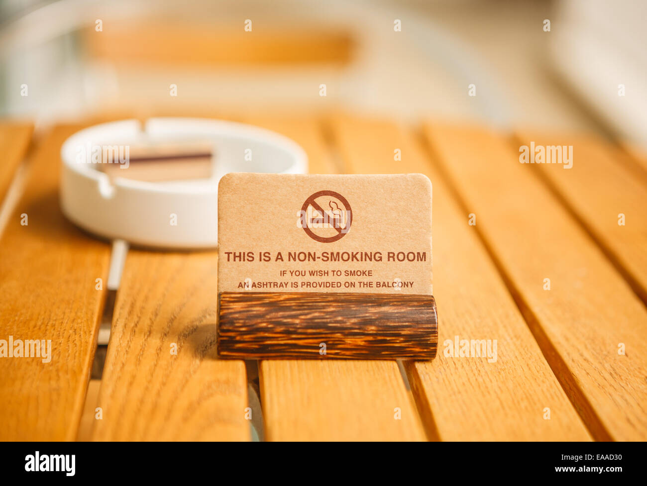 Ein Nichtraucher-Zimmer Zeichen auf Kokosnuss ruhen mit einem weißen Keramik Aschenbecher und passen auf einem Holztisch in einem Hotelbalkon Stockfoto