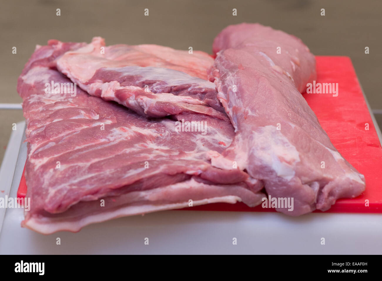 Gemeinsames Schweinefleisch auf einem roten Schneidebrett rohes Fleisch Stockfoto