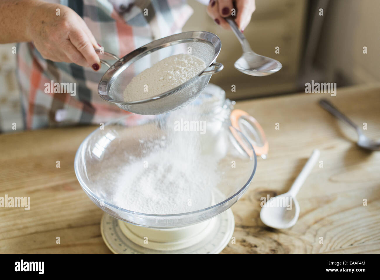 Eine Frau Mess- und weißes Mehl durchsieben. Zuhause backen. Stockfoto