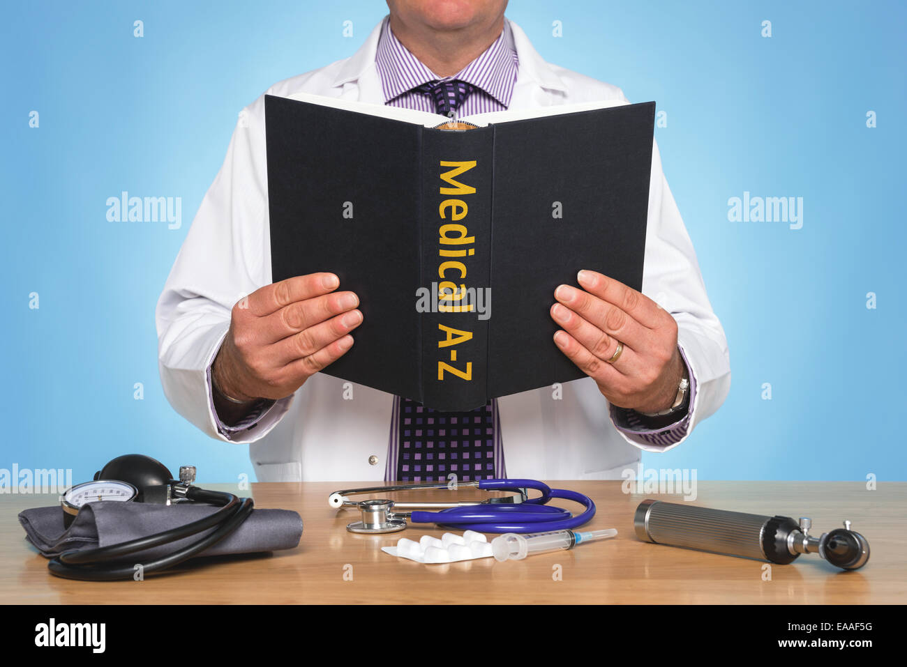 Arzt saß an einem Schreibtisch, einem medizinischen A-Z Buch Stockfoto