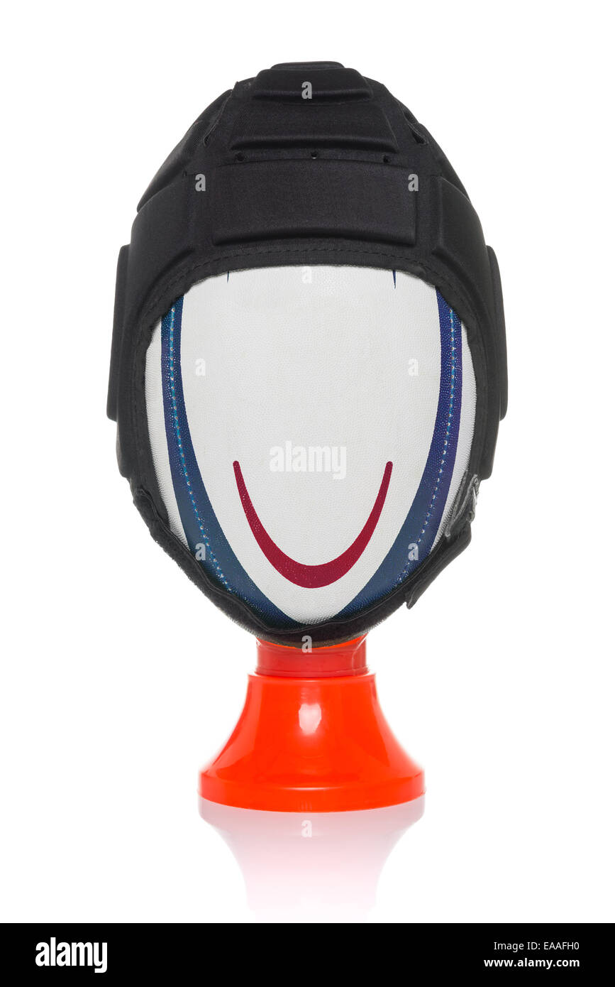 Einem Rugby-Ball mit einem gemalten Lächeln tragen einen Kopfschutz auf einem munter t-Shirt, isoliert auf einem weißen Hintergrund. Stockfoto