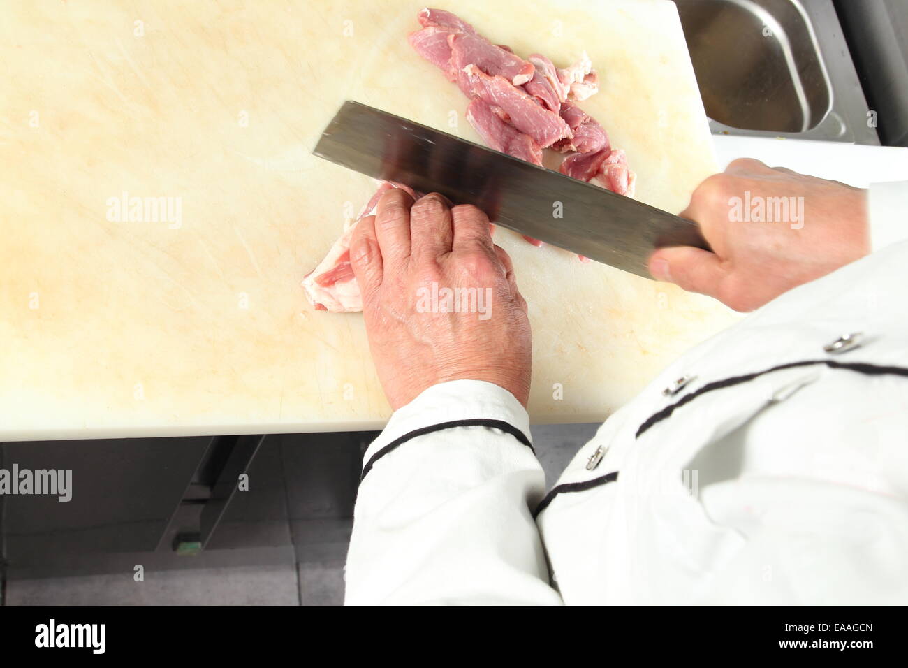 Ein Koch schneiden roh Treffen mit großen Messer Stockfoto