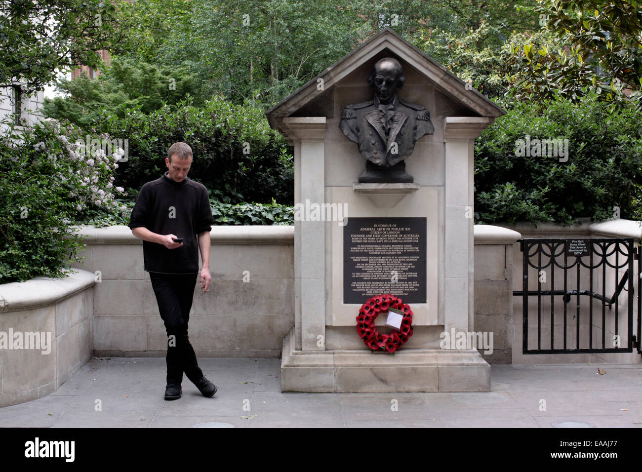 Mann mit einer Zigarette und sein Handy in der Nähe ein Kriegsdenkmal in The City, London Stockfoto