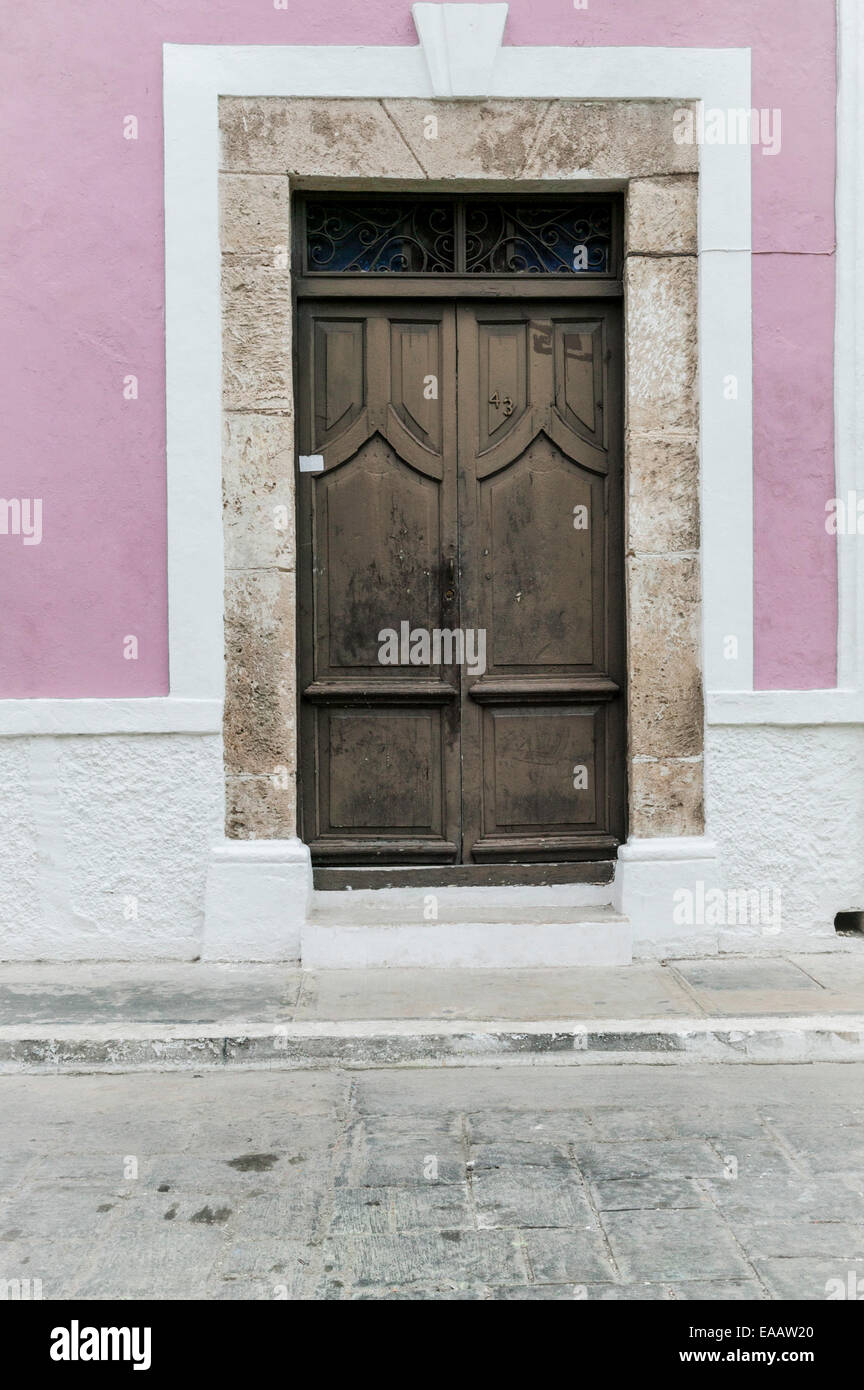 Nahaufnahme eines großen braunen Holztür mit Stein Türverkleidungen auf einem rosafarbenen und weißen Stuck spanische Kolonialgebäude, Campeche, Mexiko Stockfoto