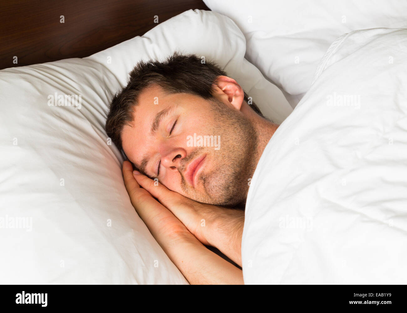 Ein schlafender Mann im Bett mit seinem Kopf auf seine Hände Stockfoto