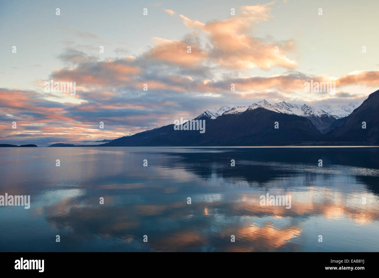 Sonnenuntergang Wolken reflektiert im ruhigen Wasser des Chilkat Inlet in der Nähe von Haines Alaska mit Schnee bedeckt Berge im Hintergrund. Stockfoto