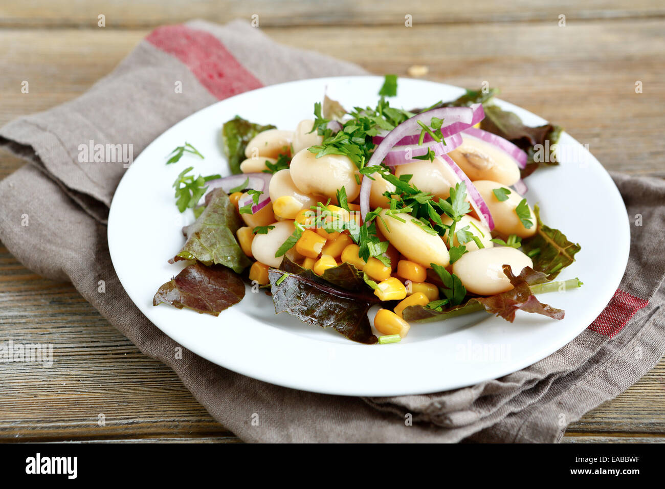 Leckeren Salat mit Bohnen, Salat, Zwiebeln und Mais auf einem Teller, Gemüse Stockfoto