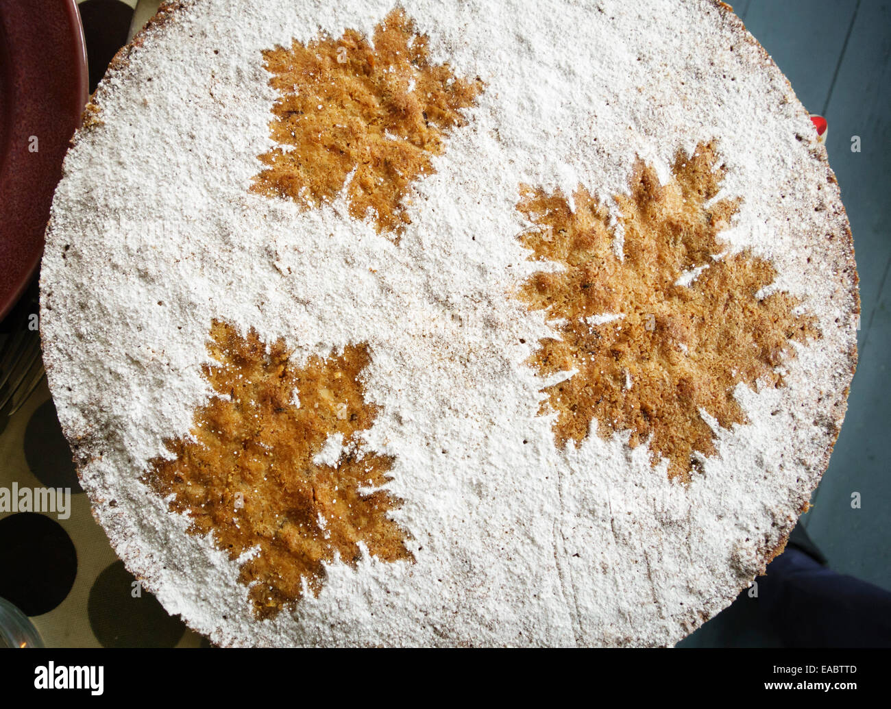 Hausgemachter Mandelkuchen mit einem Muster aus Puderzucker über Geranienblättern, die dann entfernt werden (UK) Stockfoto
