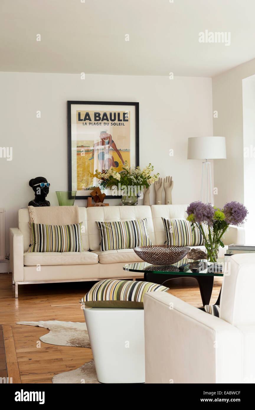 Großen weißen Knöpfen Sofa mit gestreiften Kissen im Wohnzimmer mit gerahmten Vintage poster Stockfoto