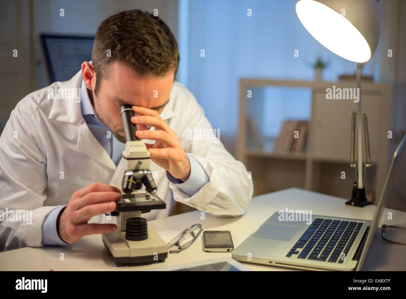 Blick auf einen jungen attraktiven Wissenschaftler arbeiten spät im Büro Stockfoto