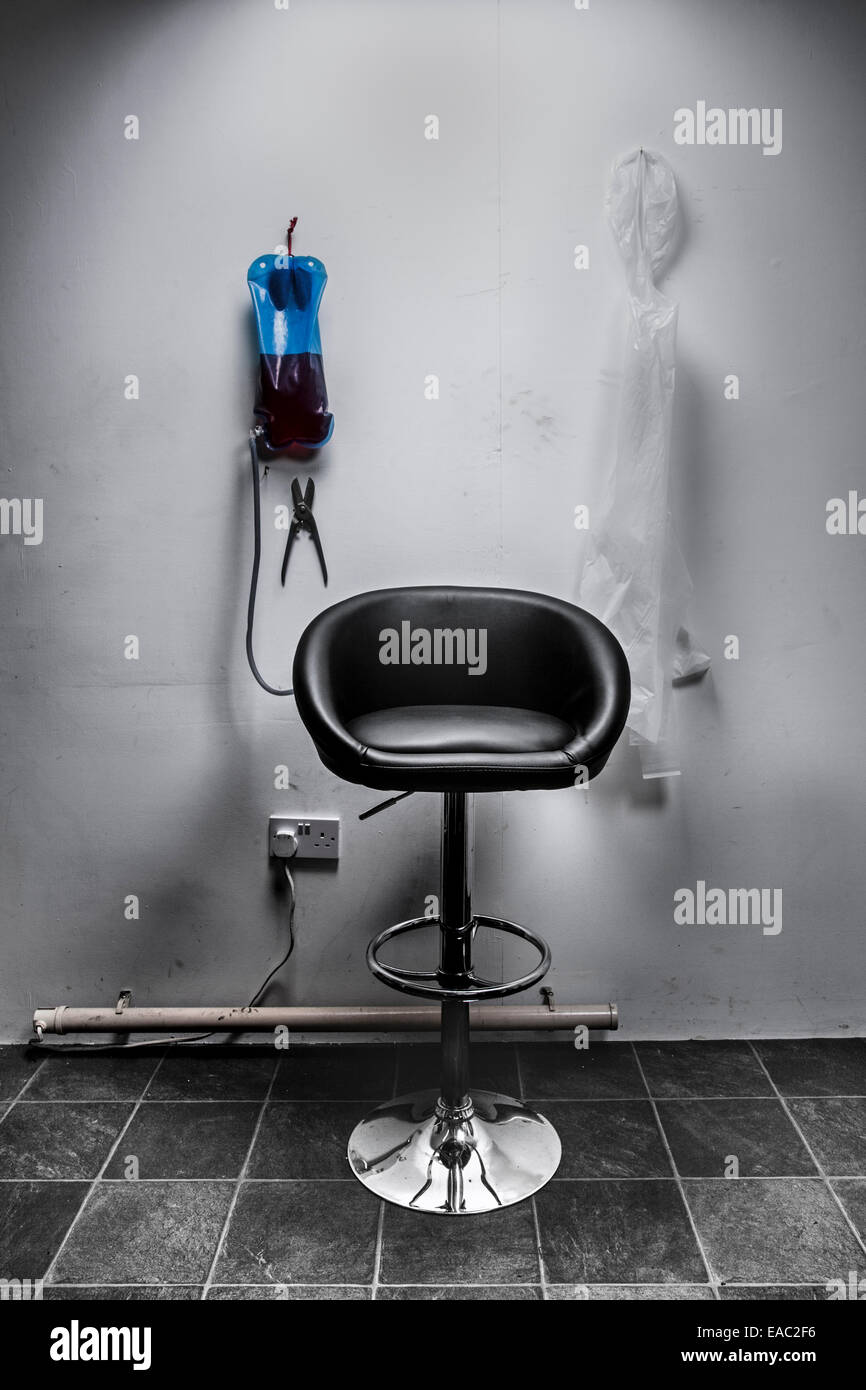 Ein Stuhl in einem beunruhigenden Raum mit Blutbeutel und Kunststoff Schürze. Stockfoto