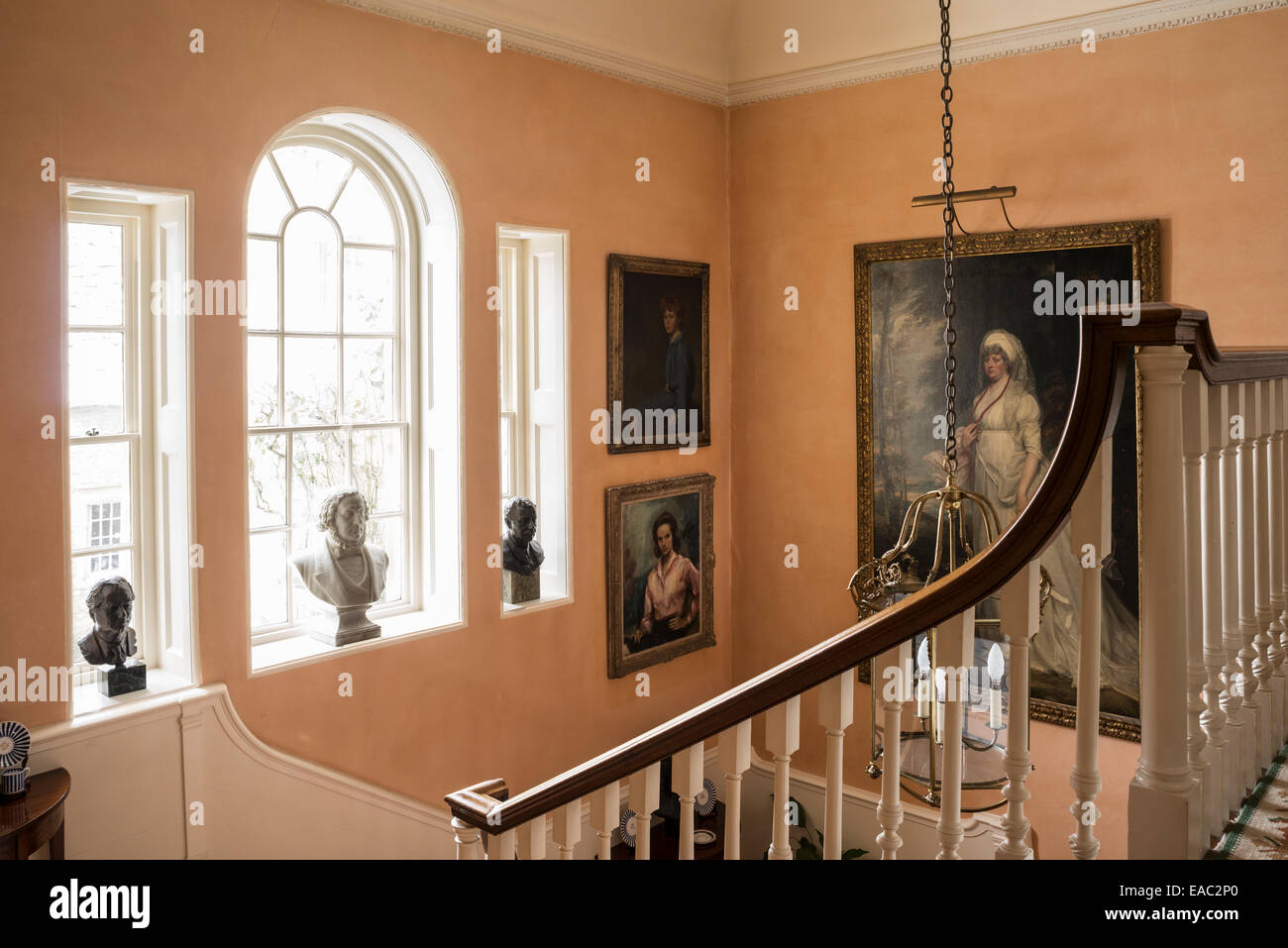 Porträts und Büsten schauen hinunter auf Treppe mit Geländer Stockfoto